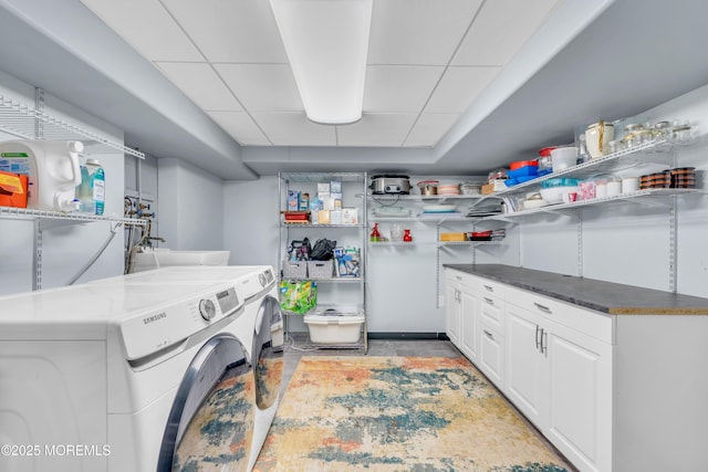 clothes washing area featuring separate washer and dryer and cabinet space