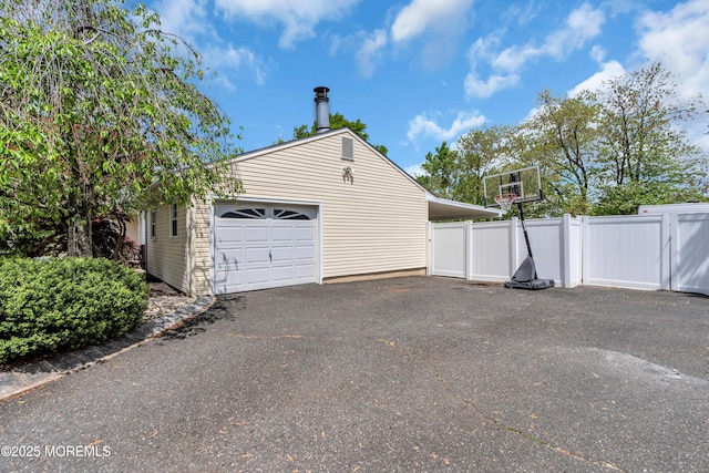 garage with fence, driveway, and a gate