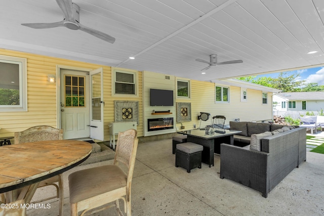 view of patio with an outdoor living space with a fireplace, outdoor dining space, and a ceiling fan