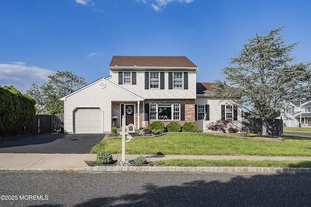 colonial-style house with a garage, asphalt driveway, and brick siding