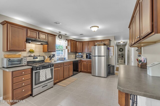 2465 Woodland Rd, Manchester, NJ 08759 - kitchen featuring stainless steel appliances, under cabinet range hood, a sink, backsplash, and brown cabinets