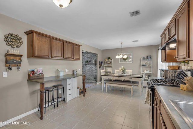2465 Woodland Rd, Manchester, NJ 08759 - kitchen featuring under cabinet range hood, stainless steel gas range oven, dark countertops, a sink, and a kitchen bar