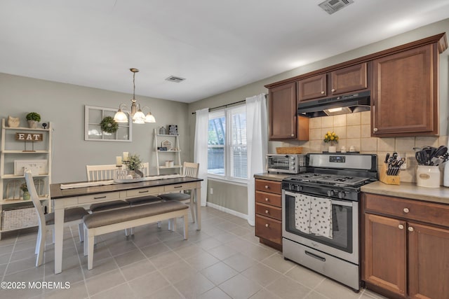 2465 Woodland Rd, Manchester, NJ 08759 - kitchen featuring under cabinet range hood, gas range, a chandelier, decorative backsplash, and decorative light fixtures