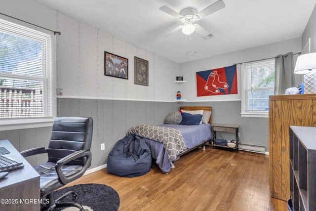 2465 Woodland Rd, Manchester, NJ 08759 - bedroom with wood finished floors, an office area, wainscoting, ceiling fan, and a baseboard heating unit