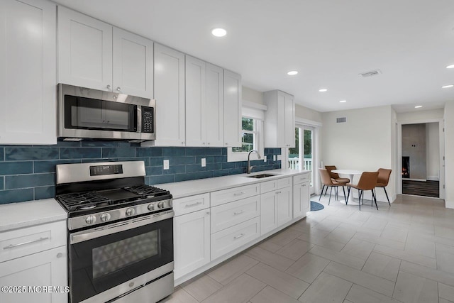 523 Norwood Ave, Long Branch, NJ 07740 - kitchen featuring stainless steel appliances, a sink, light countertops, decorative backsplash, and white cabinetry