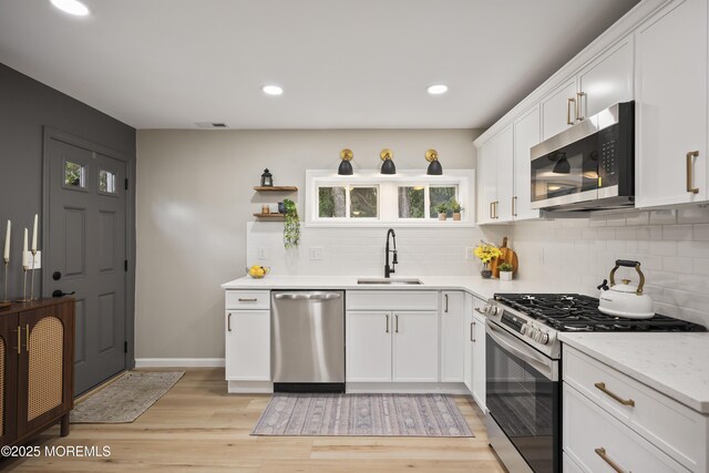 kitchen featuring stainless steel appliances, a sink, tasteful backsplash, white cabinetry, and recessed lighting