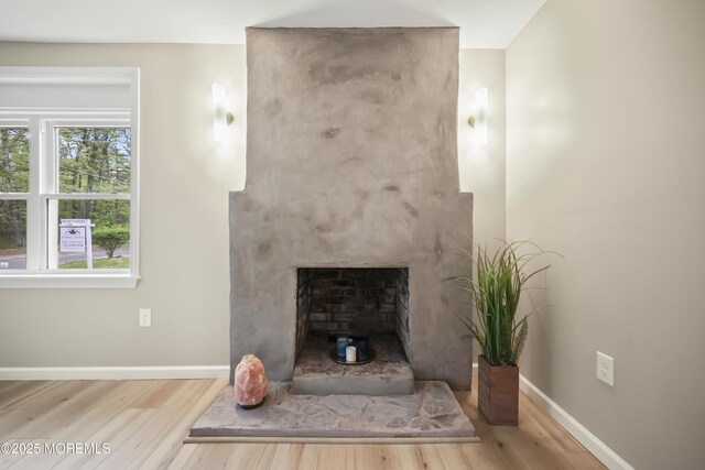 unfurnished living room with wood finished floors, baseboards, and a large fireplace