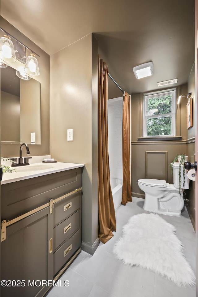 full bath with toilet, vanity, shower / bath combo with shower curtain, tile patterned floors, and baseboards