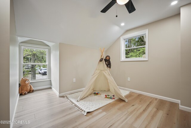 playroom featuring ceiling fan, wood finished floors, vaulted ceiling, plenty of natural light, and baseboards