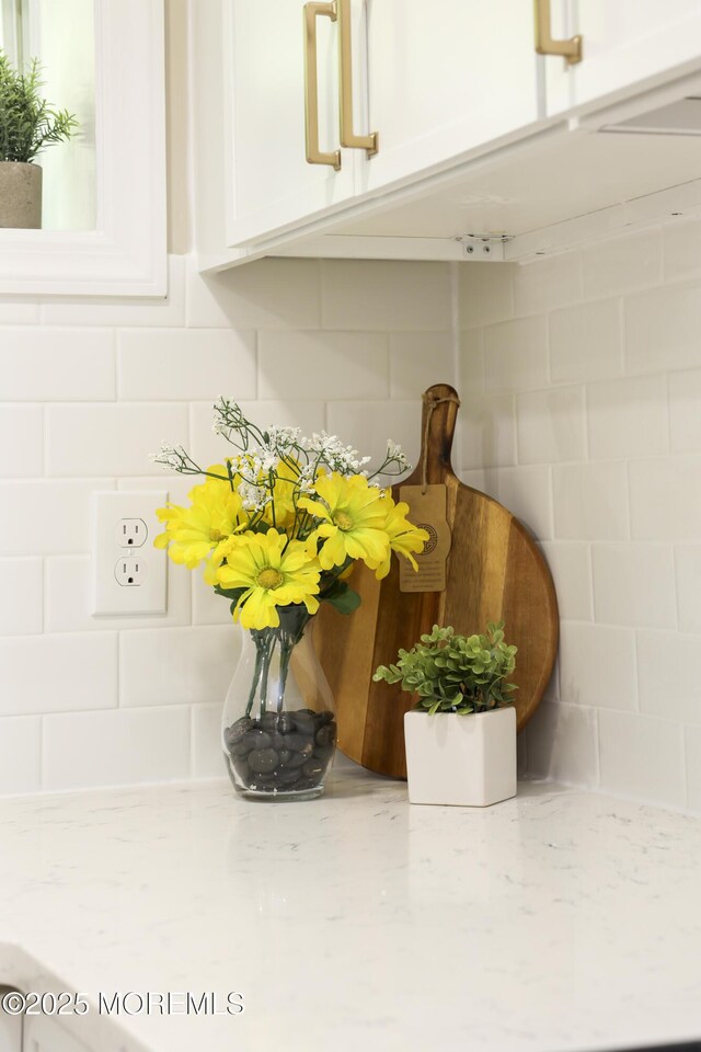 kitchen view of white cabinets, light stone countertops, and decorative backsplash