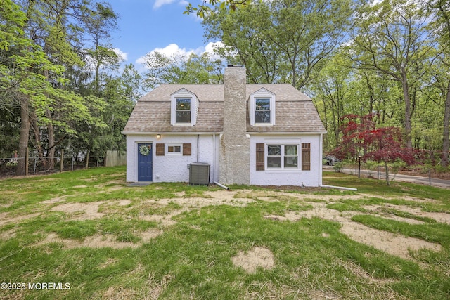 back of house featuring a chimney, central AC unit, and roof with shingles