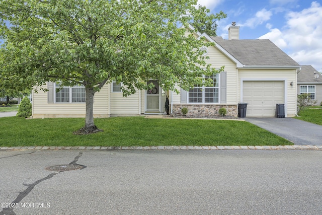 view of property hidden behind natural elements featuring asphalt driveway, a garage, a chimney, and a front lawn