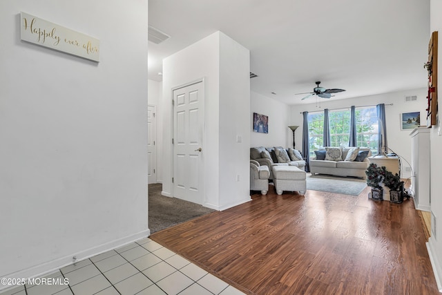 living room featuring a ceiling fan, baseboards, and wood finished floors