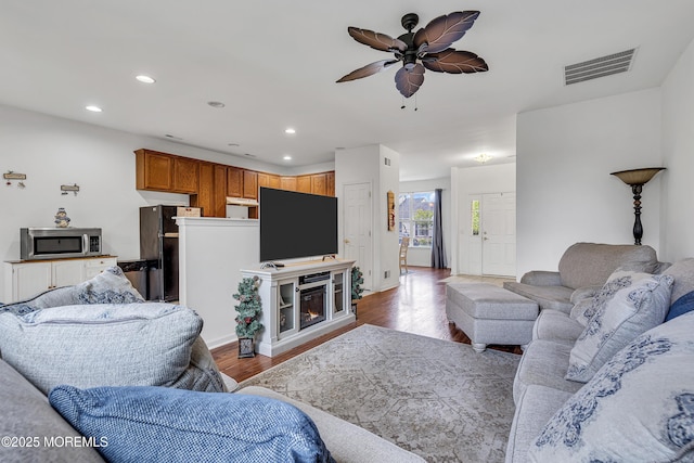 living room featuring wood finished floors, ceiling fan, recessed lighting, and a glass covered fireplace
