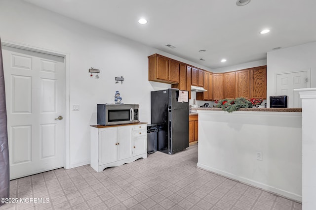 kitchen with stainless steel microwave, freestanding refrigerator, light floors, under cabinet range hood, and recessed lighting
