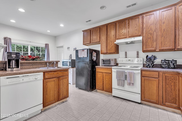 kitchen featuring white appliances, under cabinet range hood, a sink, brown cabinets, and recessed lighting