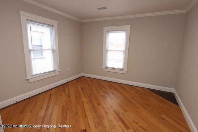 unfurnished room with plenty of natural light, wood finished floors, crown molding, and baseboards