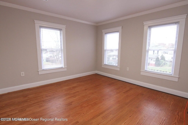 spare room featuring crown molding, light wood-style flooring, and baseboards