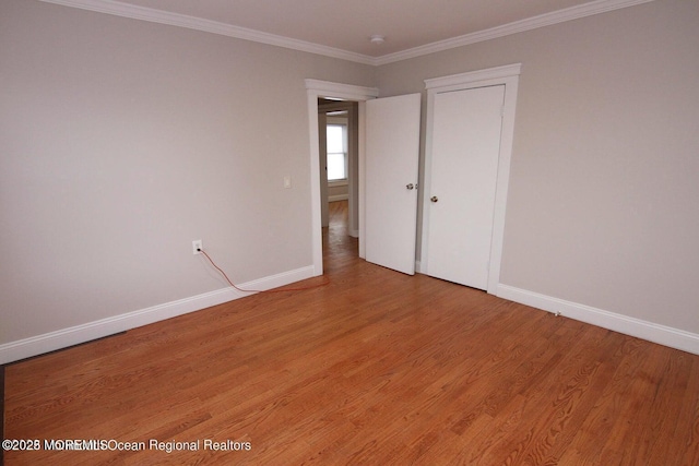 unfurnished bedroom with baseboards, light wood finished floors, and ornamental molding