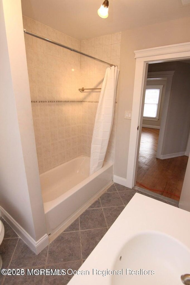 bathroom with tile patterned flooring, shower / tub combo, baseboards, and toilet