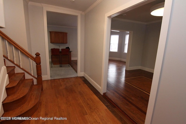 entryway with wood finished floors, crown molding, stairway, and baseboards