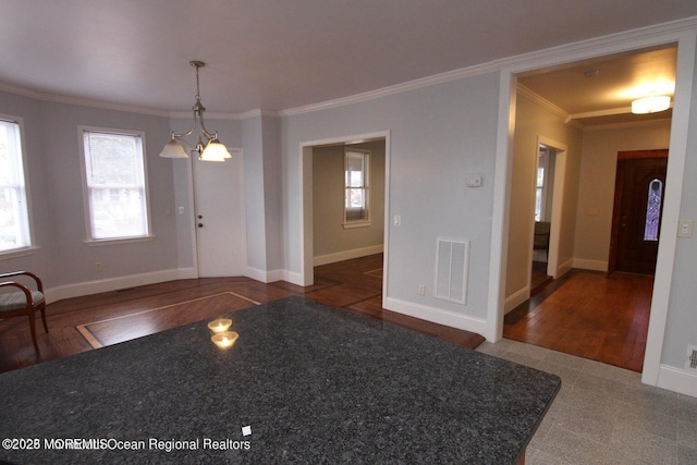 entryway with crown molding, a chandelier, baseboards, and wood finished floors