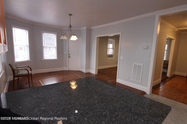 foyer with crown molding, wood finished floors, a chandelier, and baseboards