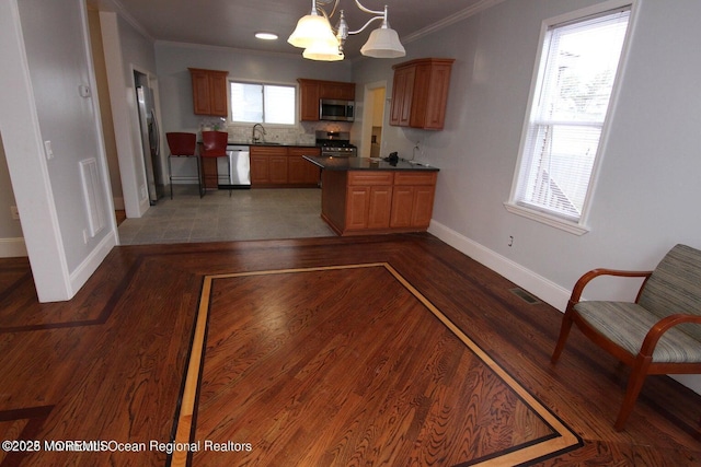 kitchen featuring appliances with stainless steel finishes, baseboards, dark countertops, a chandelier, and crown molding