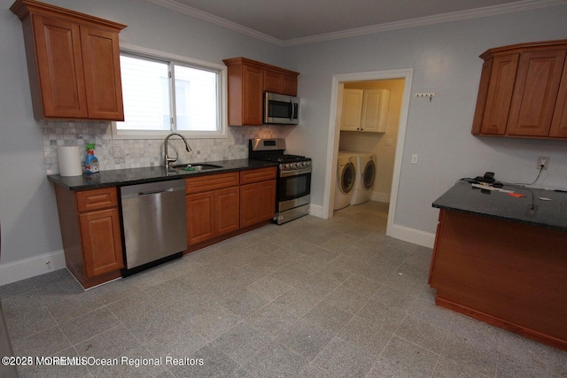 kitchen featuring appliances with stainless steel finishes, independent washer and dryer, a sink, tasteful backsplash, and brown cabinetry