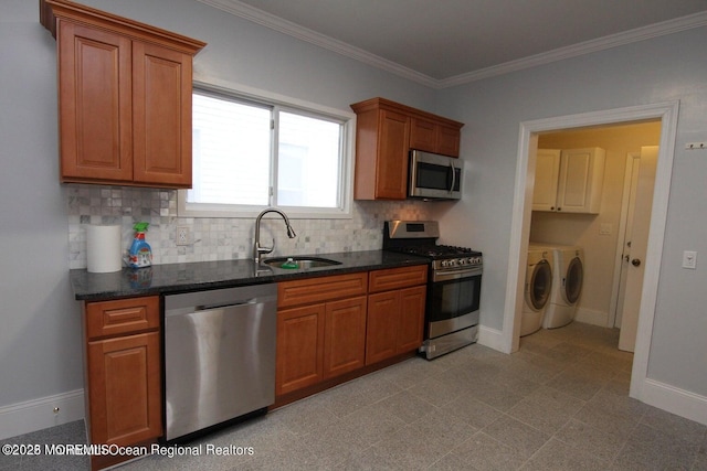 kitchen featuring appliances with stainless steel finishes, independent washer and dryer, a sink, tasteful backsplash, and ornamental molding