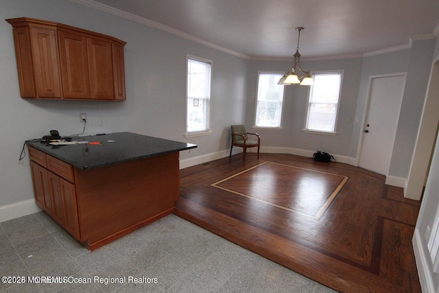 kitchen featuring brown cabinets, baseboards, crown molding, light wood-style flooring, and hanging light fixtures