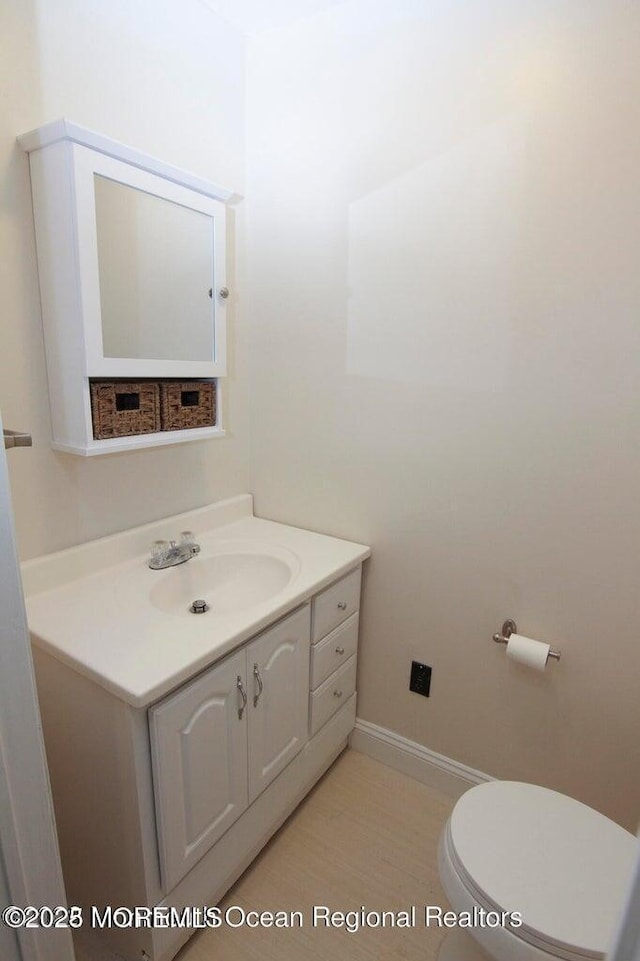 half bath with vanity, toilet, and baseboards