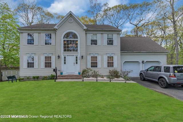 view of front facade featuring asphalt driveway, an attached garage, and a front yard