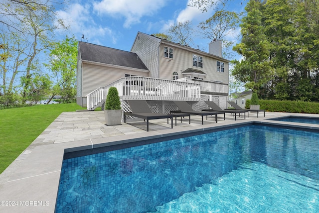 swimming pool featuring stairs, a patio area, a deck, and a lawn