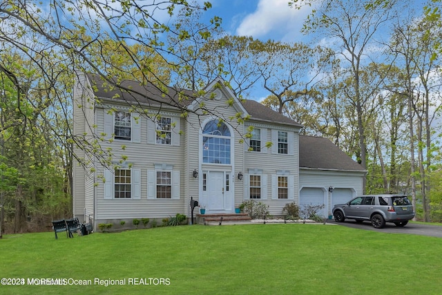 colonial home featuring a garage, a front lawn, and asphalt driveway