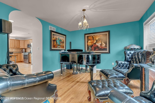 living room with a chandelier, baseboards, and light wood-style floors