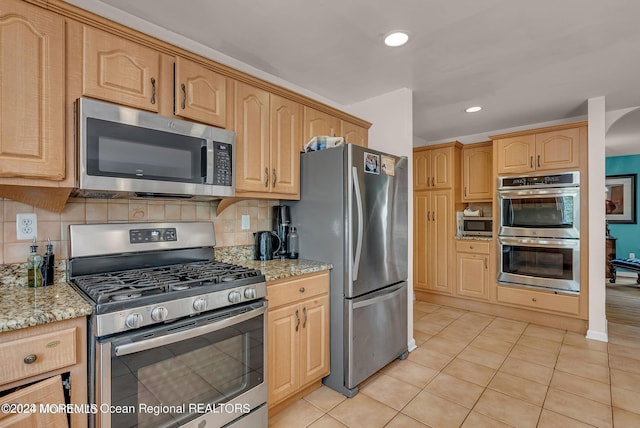 kitchen featuring stainless steel appliances, light stone counters, light tile patterned floors, tasteful backsplash, and recessed lighting