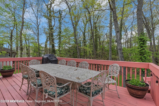 wooden deck with outdoor dining space and a grill