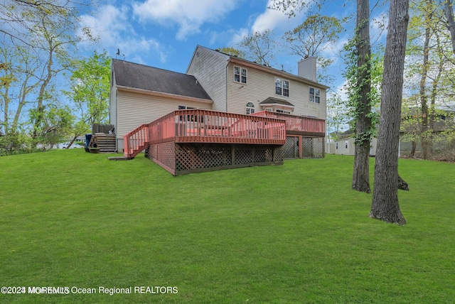back of house with a deck, a chimney, and a lawn
