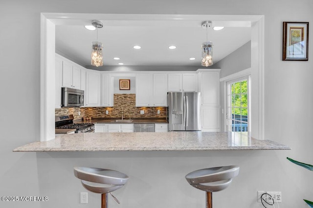 59 Inwood Dr, Manalapan, NJ 07726 - kitchen with appliances with stainless steel finishes, a peninsula, decorative backsplash, white cabinets, and recessed lighting