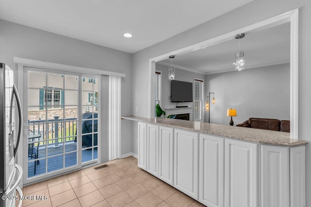 59 Inwood Dr, Manalapan, NJ 07726 - kitchen with stainless steel fridge with ice dispenser, white cabinets, a fireplace, a chandelier, and pendant lighting