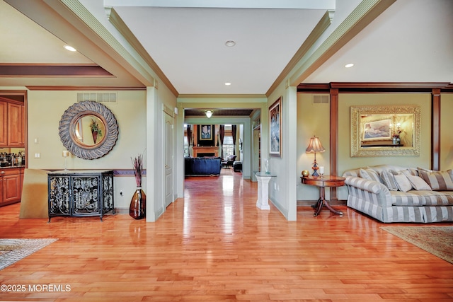 hall featuring crown molding, light wood-style flooring, baseboards, and recessed lighting