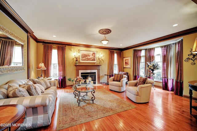 living room with ornamental molding, hardwood / wood-style flooring, a fireplace with flush hearth, baseboards, and recessed lighting