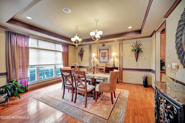 dining area with a tray ceiling, a chandelier, light wood-type flooring, crown molding, and baseboards