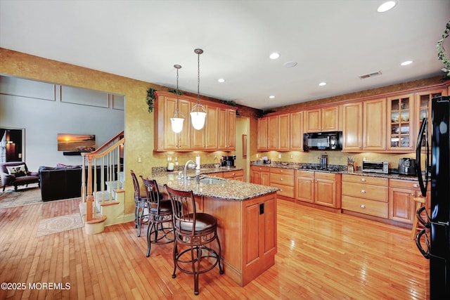 kitchen with black appliances, light wood-style flooring, a sink, a peninsula, and recessed lighting