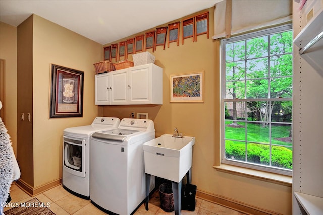 laundry area featuring washer and clothes dryer, light tile patterned floors, cabinet space, and baseboards