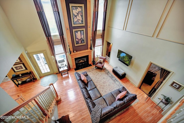 living area featuring a towering ceiling, a fireplace, and wood finished floors