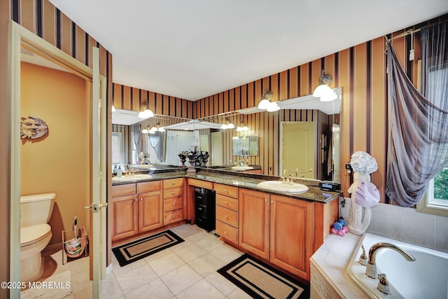 bathroom featuring toilet, double vanity, tile patterned floors, a tub, and wallpapered walls