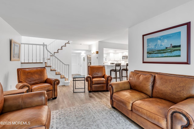 living area with light wood finished floors and stairway