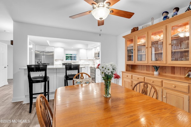 dining space with ceiling fan and light wood finished floors
